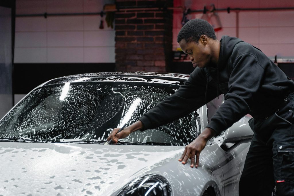 Man in Black Jacket Sitting on Car Hood