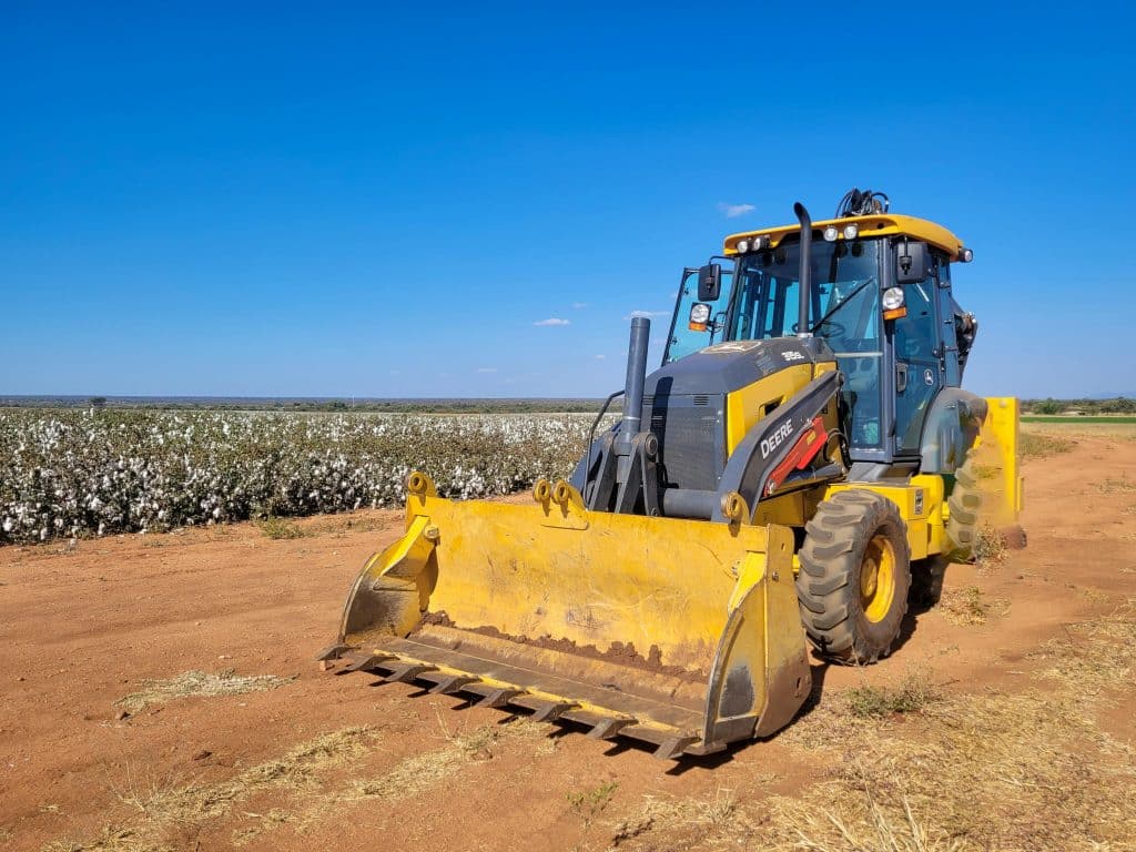 A yellow tractor in a cotton field on a sunny day showcasing agricultural machinery.